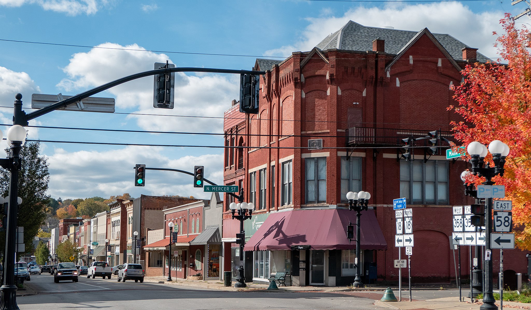 Road in a small-town business district with closely built brick buildings with storefronts and sidewalks on the street level. 
